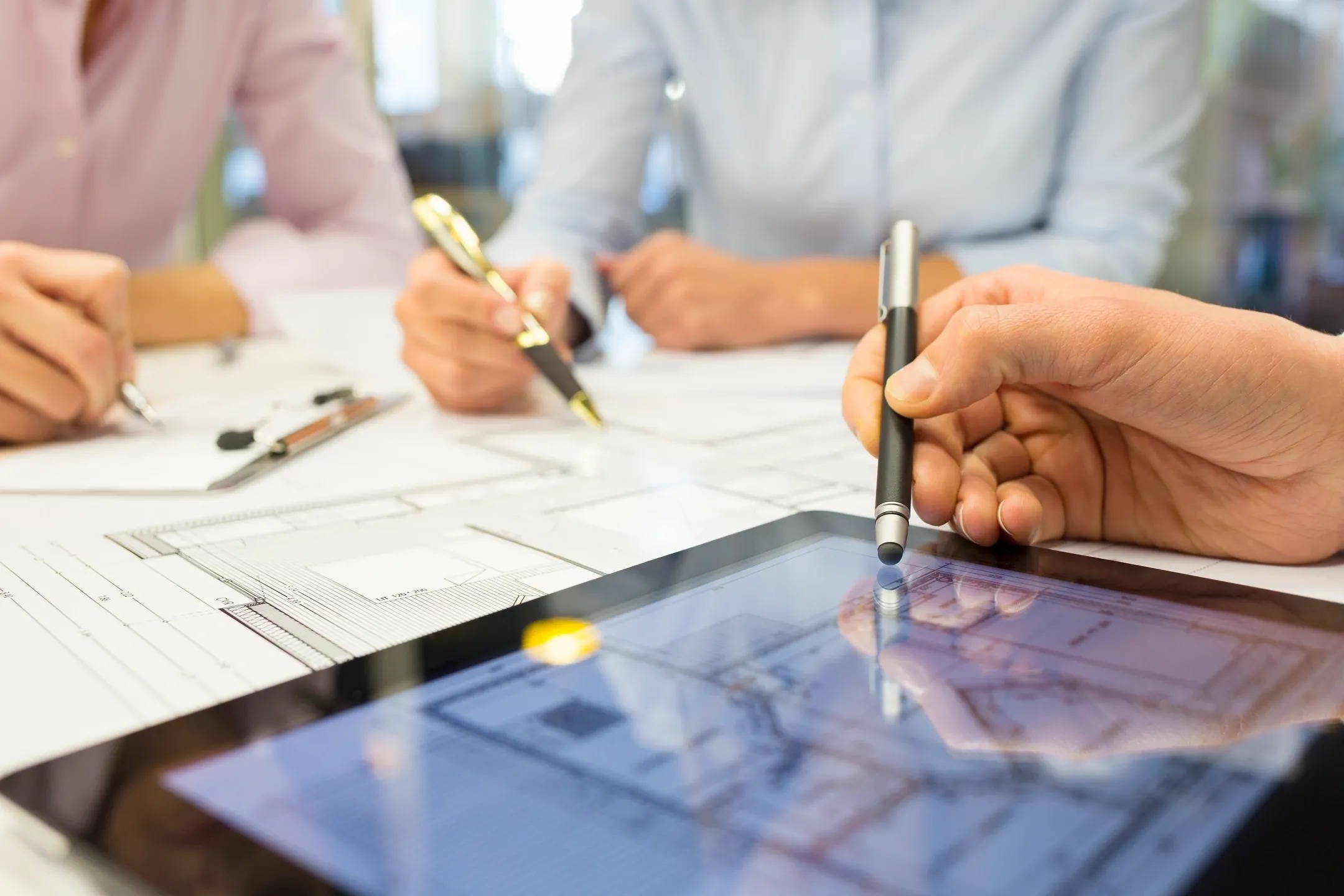 A group of people sitting around a table with pens and paper.