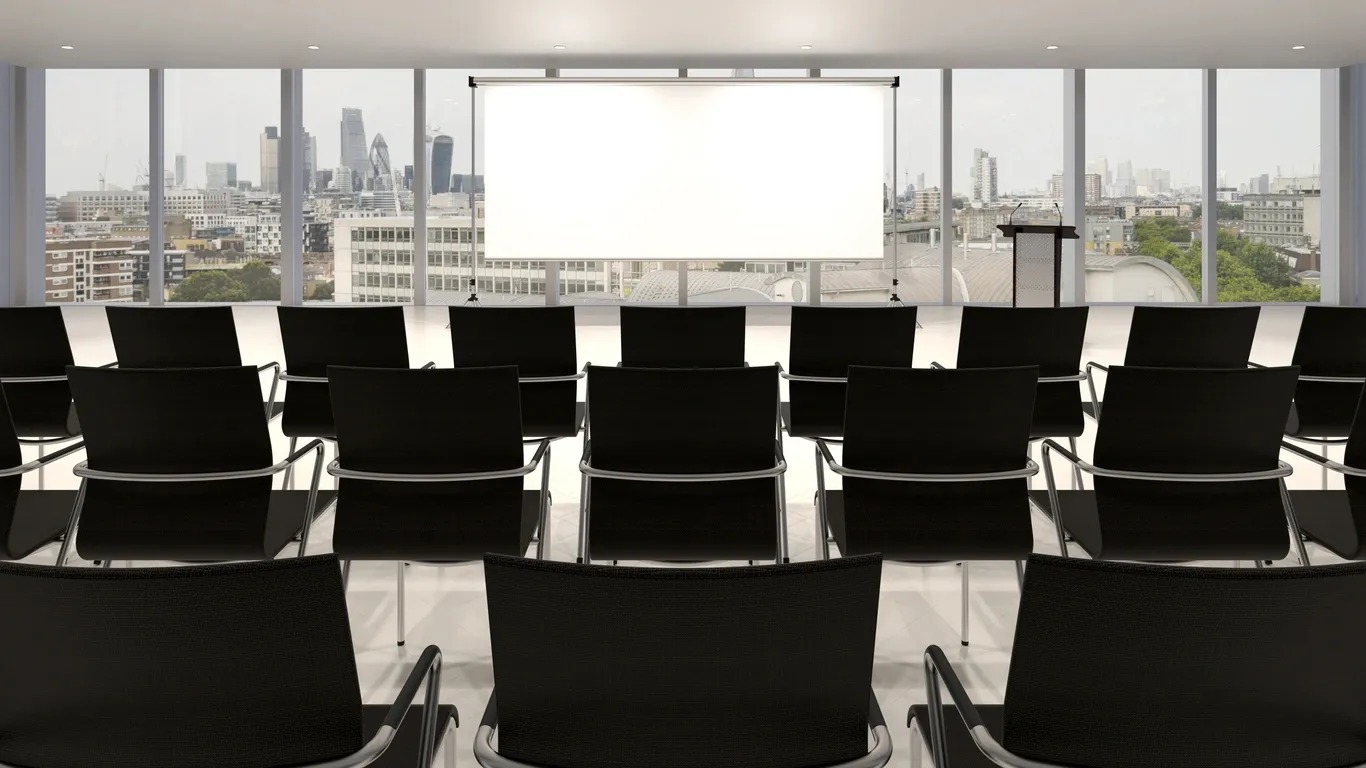 A large conference room with chairs and a projector screen.