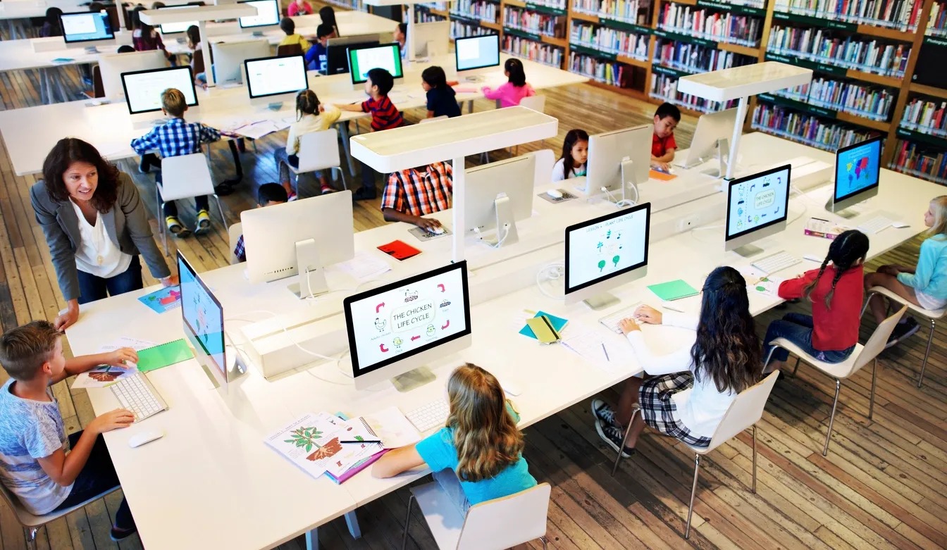 A group of children sitting at desks with computers.